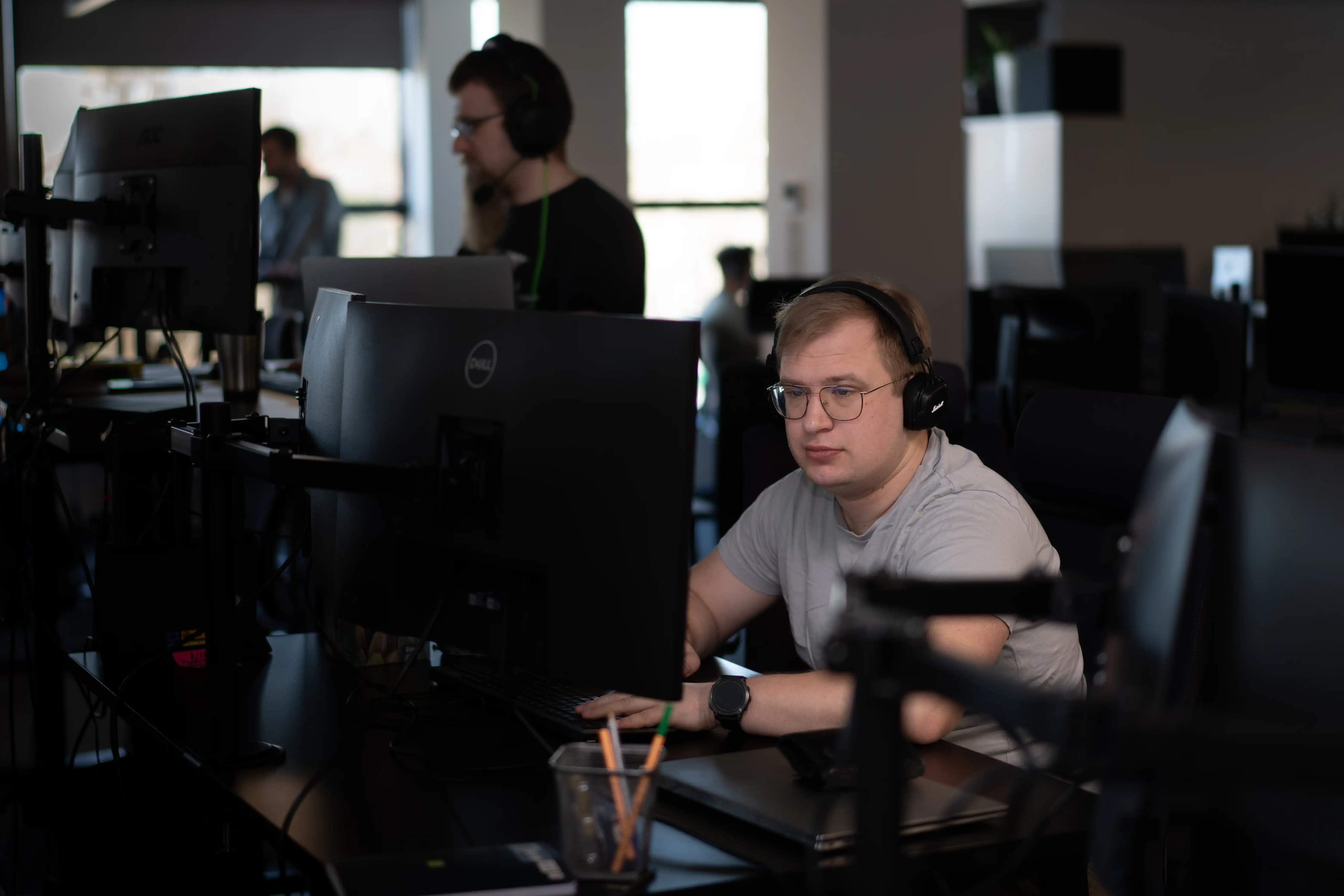 "A data professional with headphones working at a computer in the office."