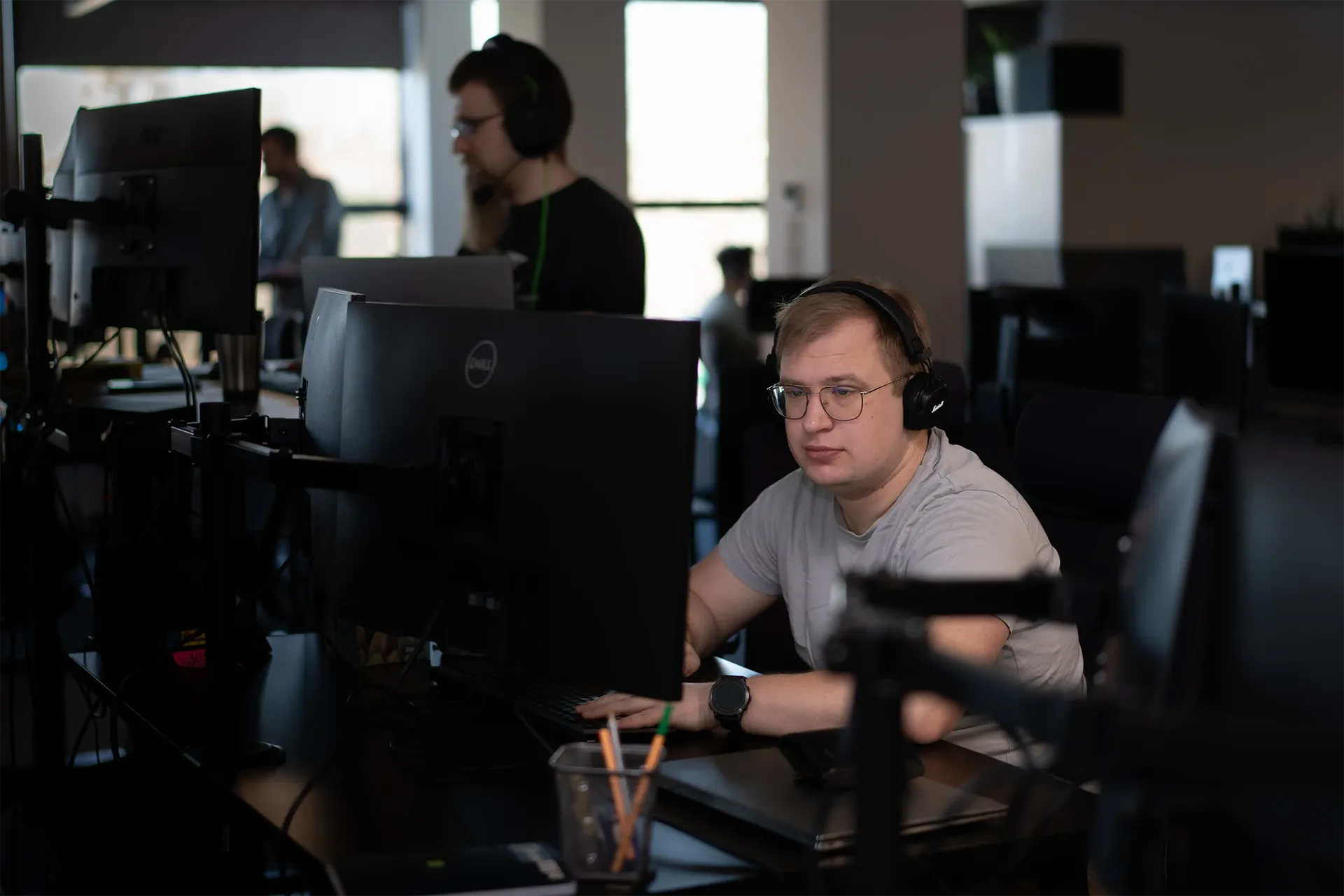 "A data professional with headphones working at a computer in the office."